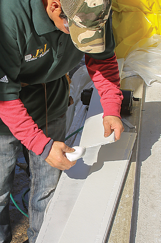 Photo of a man priming cut ends of siding stock to prevent premature paint failure and rot.
